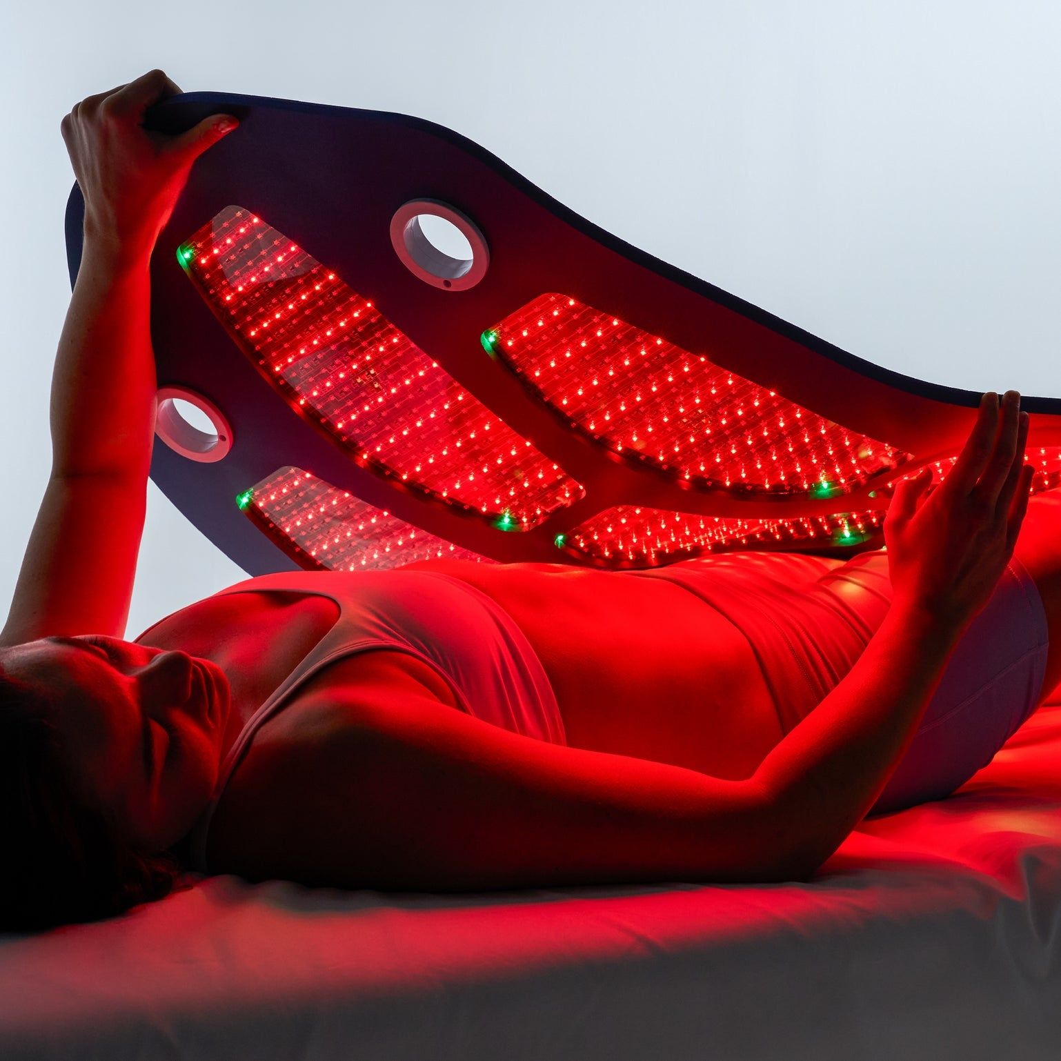 Patient lying under a Celluma LLLT panel during a fertility laser session